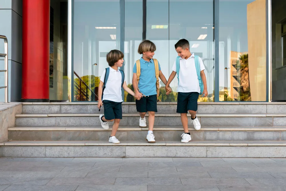 Three elementary school-aged boys step outside their school building, which has glass doors at the entrance fortified by c-bond, making them bullet resistant windows.