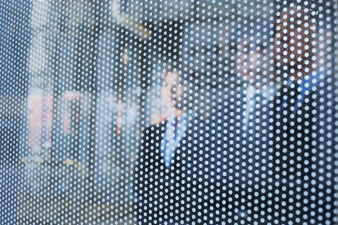 Three business people behind a glass wall looking out